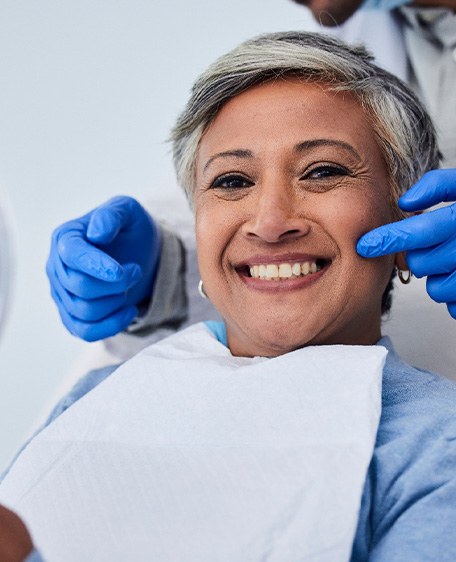 Woman smiling while holding handheld mirror