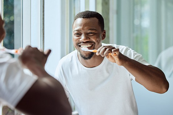 Man smiling while brushing his teeth