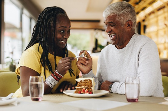 Couple smiling while eating slice of cake