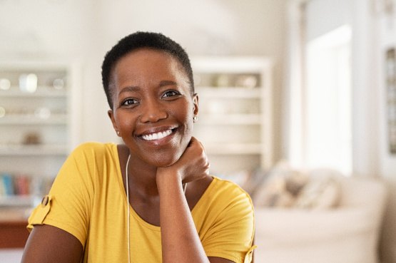 Woman in yellow shirt smiling at home