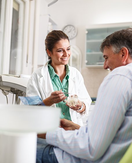 Dentist smiling while talking to patient in treatment chair