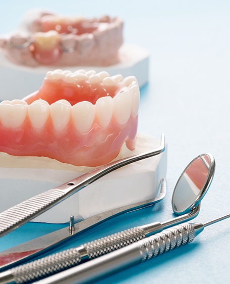 Models of dentures next to dental tools