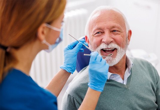 Man smiling while brushing his teeth