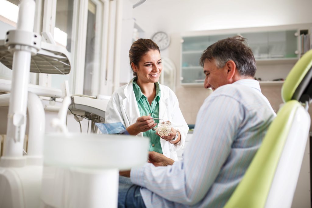 Smiling dentist talking to patient in treatment chair