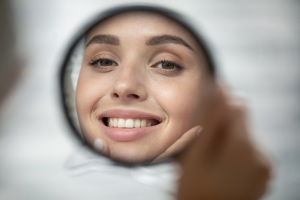 a person examining their smile in a handheld mirror